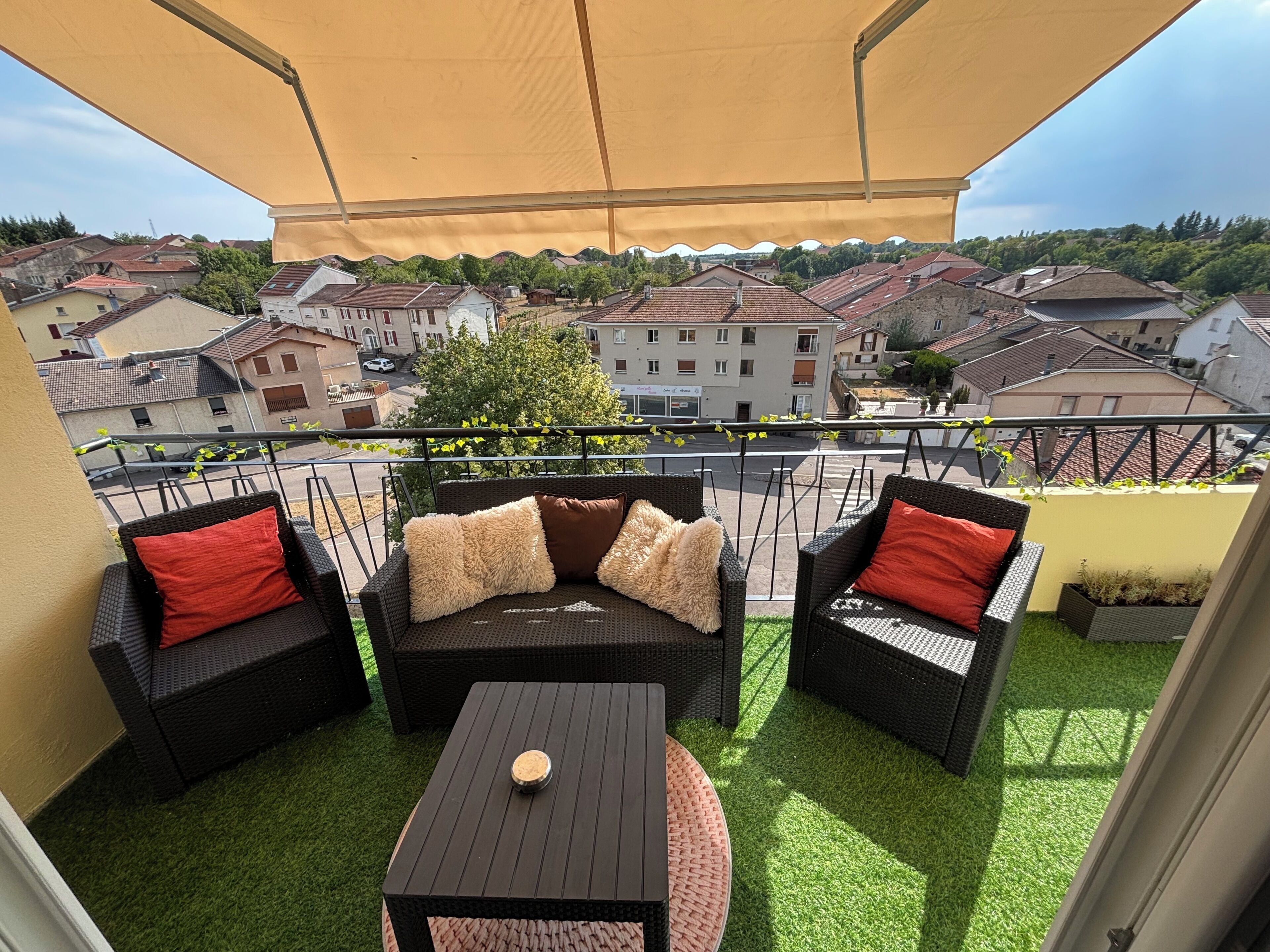 Un balcon avec des meubles d’extérieur, une vue sur le quartier et un auvent jaune.
