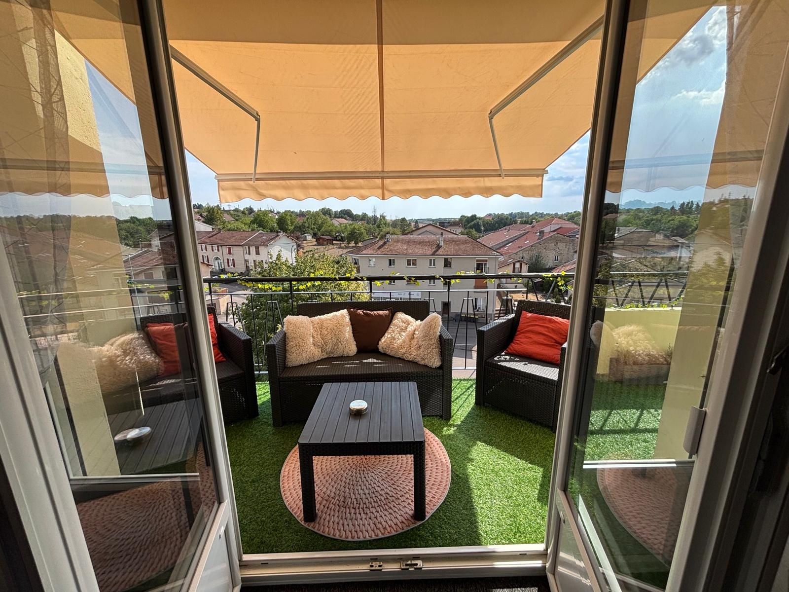 Un balcón con mobiliario exterior, una mesa y vista a una zona residencial.