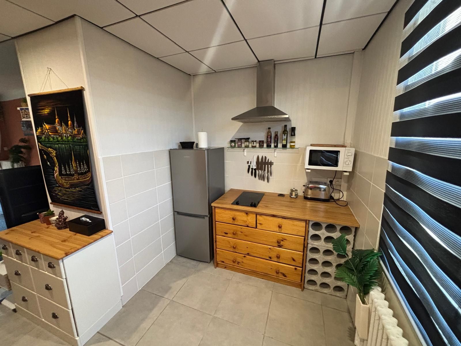 A compact kitchen with a refrigerator, microwave, and wooden counter.