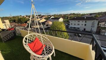 A balcony with a hanging chair, a sofa, and a small table.