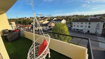 Ein Balkon mit Hängesessel, einer Couch und Blick auf eine Wohngegend.