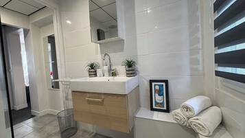 Une salle de bain moderne avec un lavabo blanc, un meuble en bois et un tableau encadré au mur.