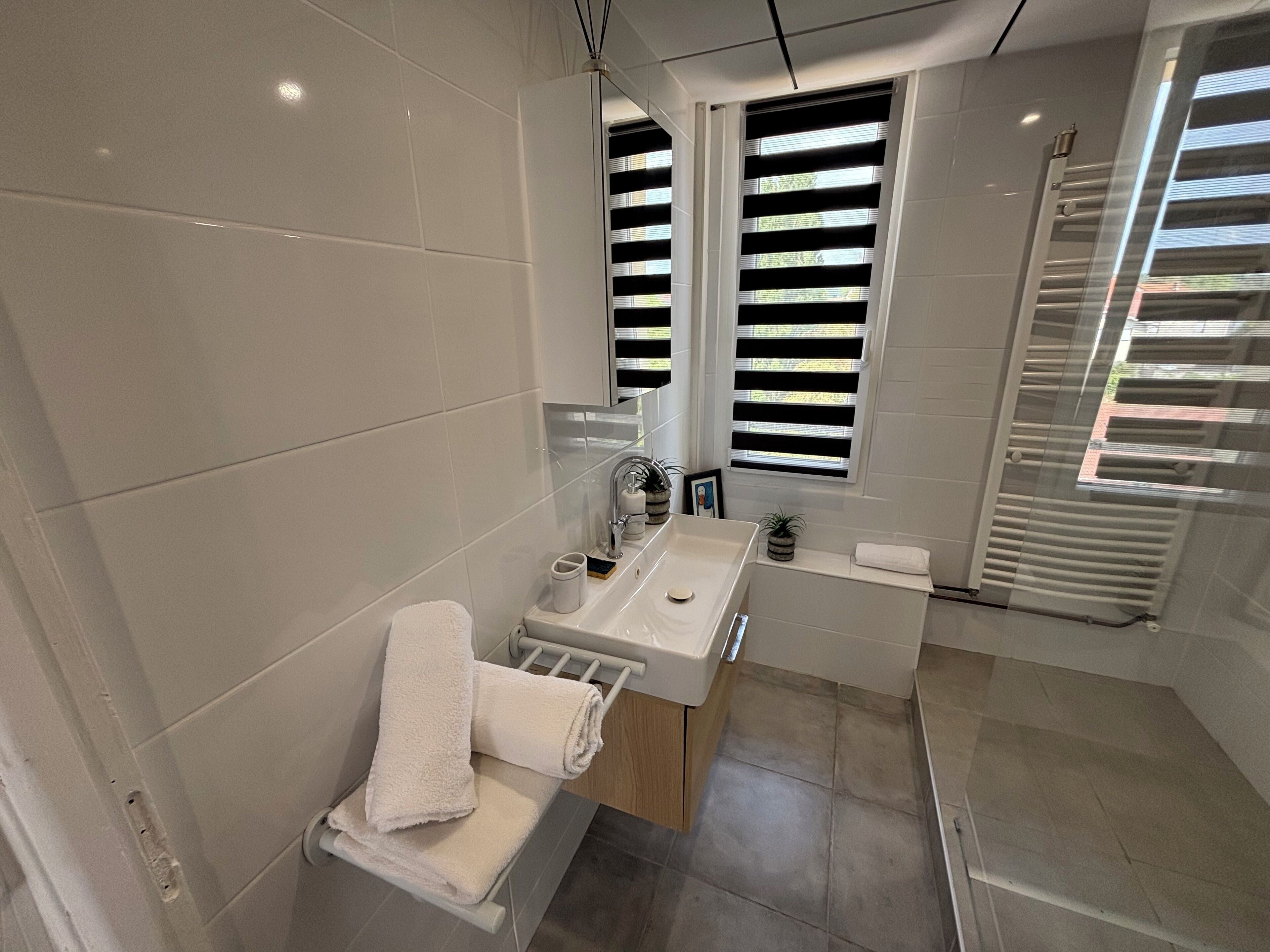 Ein modernes Badezimmer mit einem großen Spiegel, einem Waschbecken und einer Badewanne.