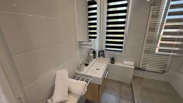 Ein modernes Badezimmer mit einem großen Spiegel, einem Waschbecken und einer Badewanne.