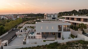 Een modern gebouw met een zwembad op het dak, omringd door groen en andere woongebouwen.