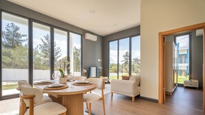 A modern interior with a dining area, large windows, and a view of the outdoors. - Lotus Villas & Suites (Polygyros)