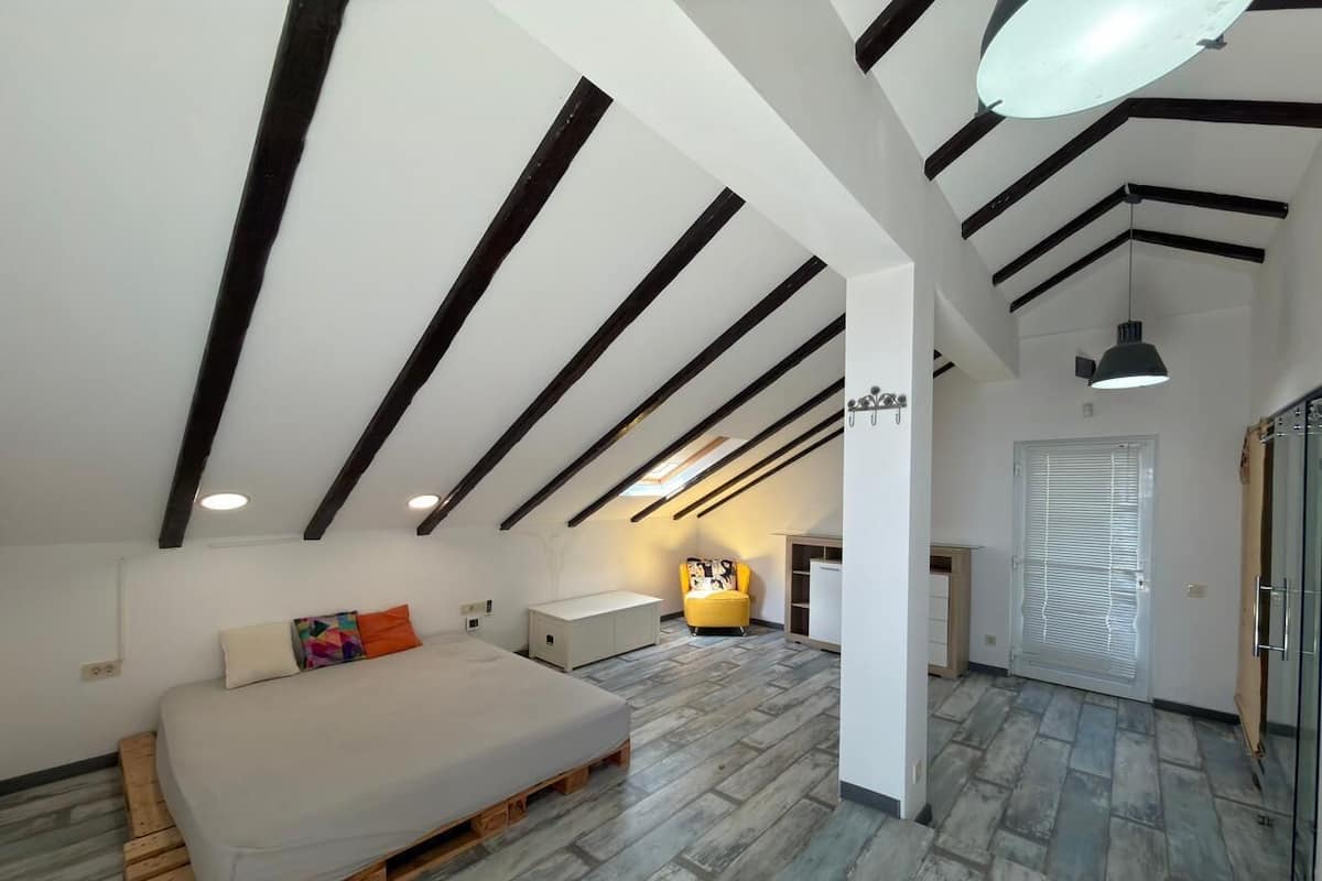 A bedroom with a bed, a chair, a small table, and a wardrobe.