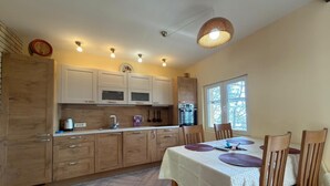 Eine Küche mit Holzschränken, einem Esstisch mit Stühlen und einer hängenden Lampe.