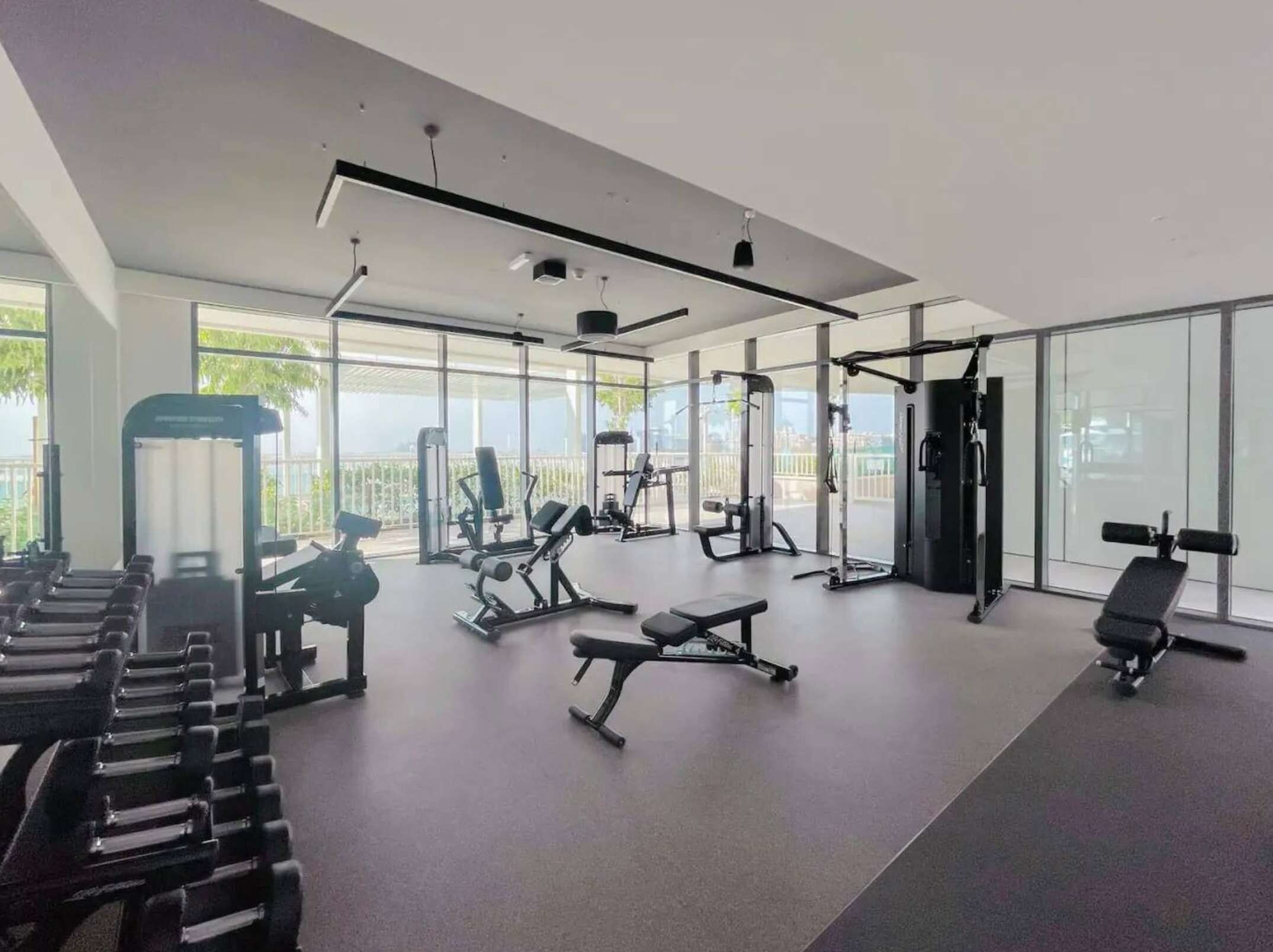 Uma academia moderna com diversos equipamentos de exercícios, janelas amplas e um layout espaçoso e limpo.