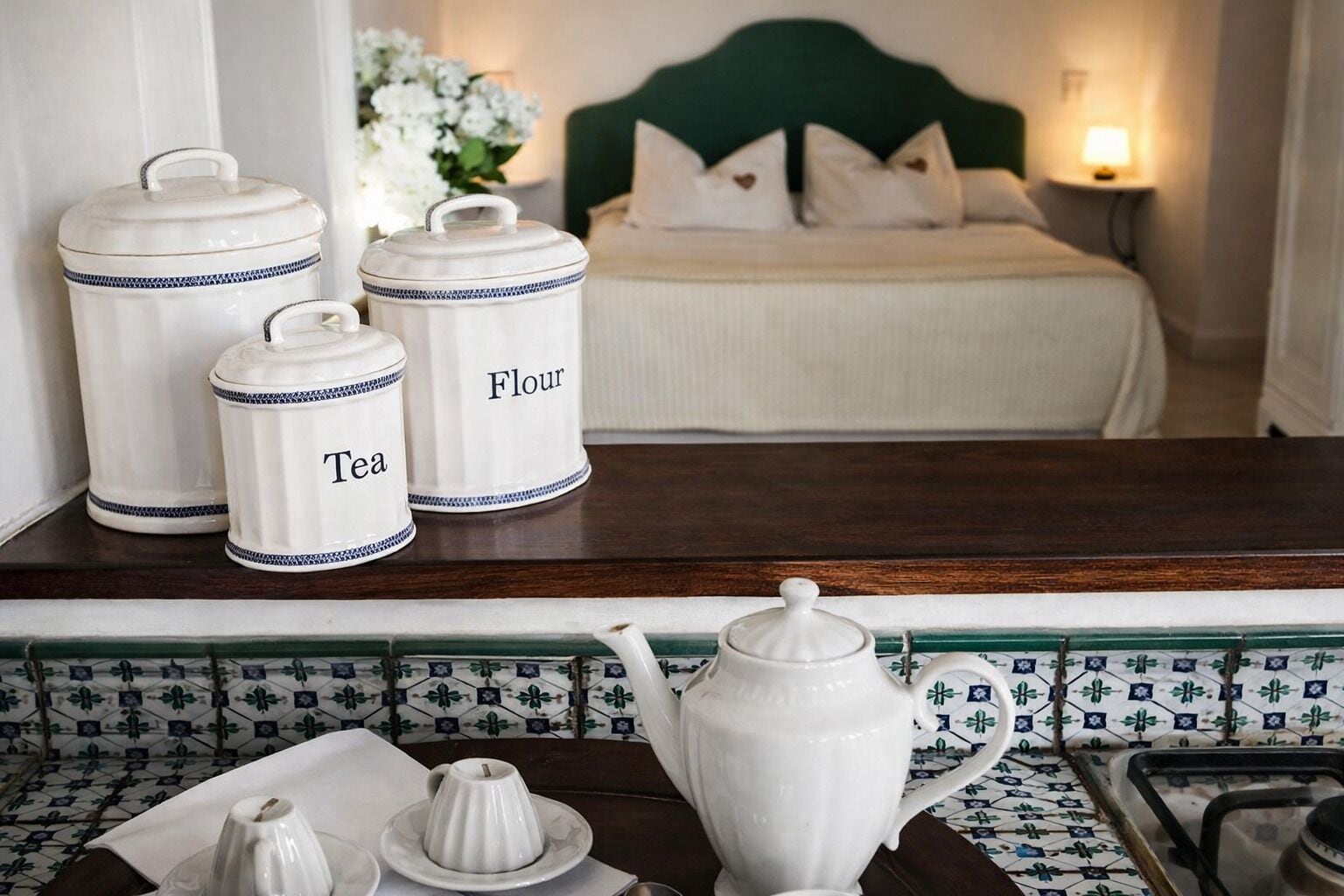 A kitchen area with a coffee maker, tea pot, and flour and tea containers on the counter.