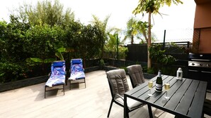 Eine Terrasse im Freien mit Tisch, Stühlen und einer Weinflasche.