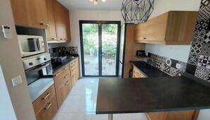 A modern kitchen with wooden cabinets, a black countertop, and a microwave. - Vacation home in Apt (Apt)
