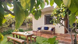 Una casa de ladrillo con un patio, una mesa de madera y una banca.