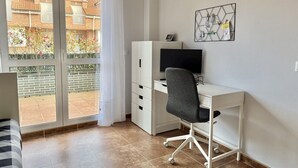 A bedroom with a bed, a desk with a computer, and a window with a view of buildings. - Apartment with large terrace - El Robledal 5925 (Isla)