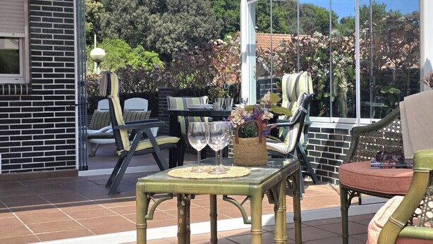 An outdoor patio with a table set for two, surrounded by chairs, and a glass enclosure. - Apartment with large terrace - El Robledal 5925 (Isla)