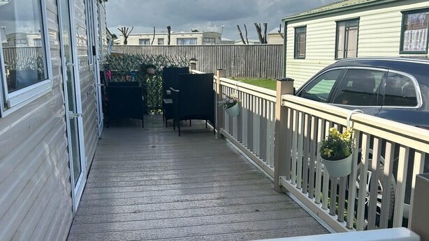 A covered outdoor area with a wooden deck, a white railing, and potted plants. - 2 Bed - Sleeps 6 - Free Parking - Pets (Skegness)