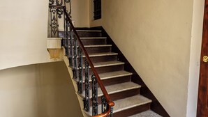 Een trap met decoratieve metalen leuningen en een houten handrail, die uitkomt op een plateau met een deur.