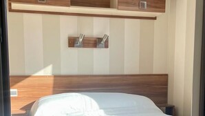 A bedroom with a bed, wooden headboard, built-in shelves, and a nightstand. - El Palmar Paradise . (El palmar, Vejer de la frontera)