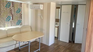 A room with a sofa, a table, an air conditioning unit, and a door leading to a bathroom. - El Palmar Paradise . (El palmar, Vejer de la frontera)