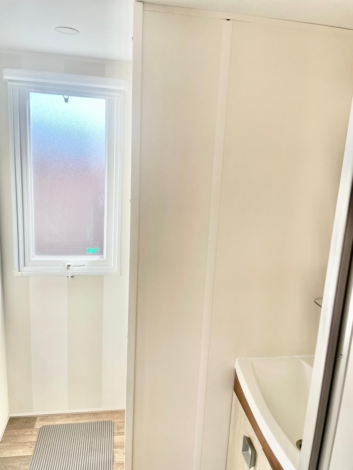 A room with a window, a door, a radiator, and a sink.