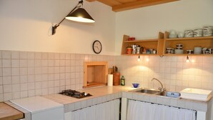 A kitchen with a sink, stove, and wooden shelves above the counter.