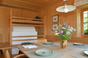 A wooden interior with a dining table, chairs, a vase with flowers, and shelves with bedding. - Holiday Home 'Kohlstatt Hof Ferienhaus' with Mountain View, Private Terrace & Wi-Fi (Verano)