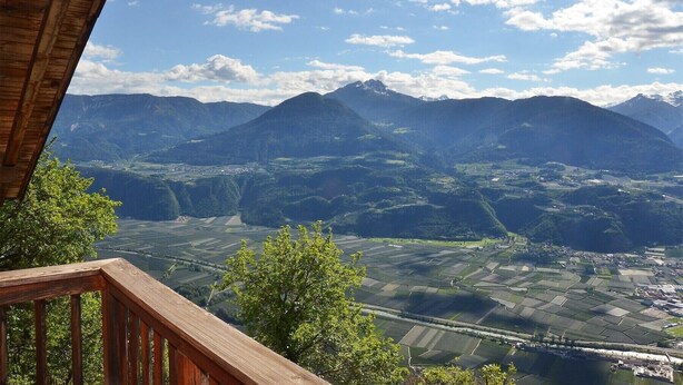 A mountainous landscape with fields and a wooden structure in the foreground.