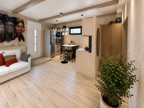Un soggiorno moderno con divano, angolo da pranzo con tavolo e sedie, e zona cucina con elettrodomestici.