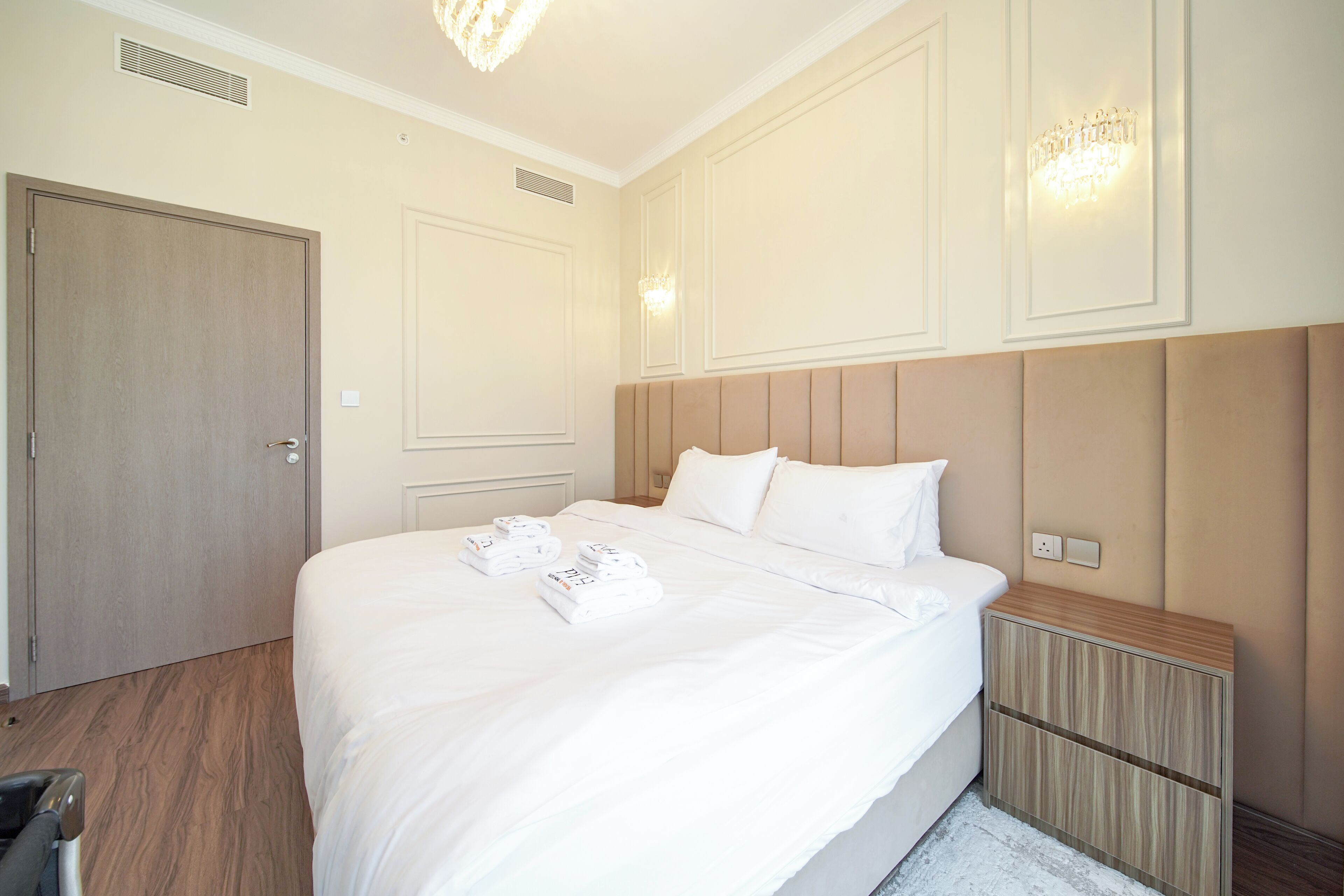 Een hotelkamer met een groot bed, een houten hoofdbord, een nachtkastje en een deur.