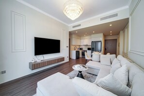 Ein modernes Wohnzimmer mit Flachbildfernseher, einer Couch, einem Couchtisch und einer Kristallleuchter.