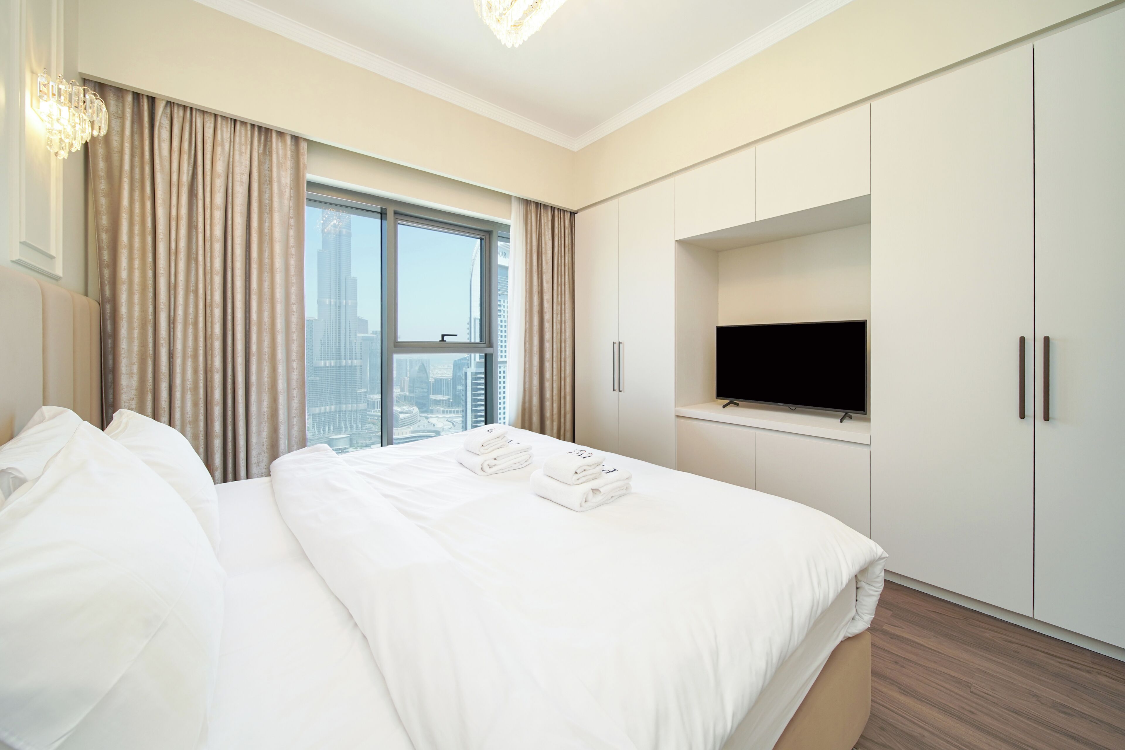 A hotel room with a large bed, a television, and a city view.