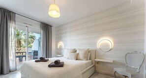 A bedroom with a bed, two bedside tables, a chair, a large window with curtains, and a view of the outdoors. - Riviera Paradise | Terrace, Pools & Views REF902 (La Cala de Mijas)