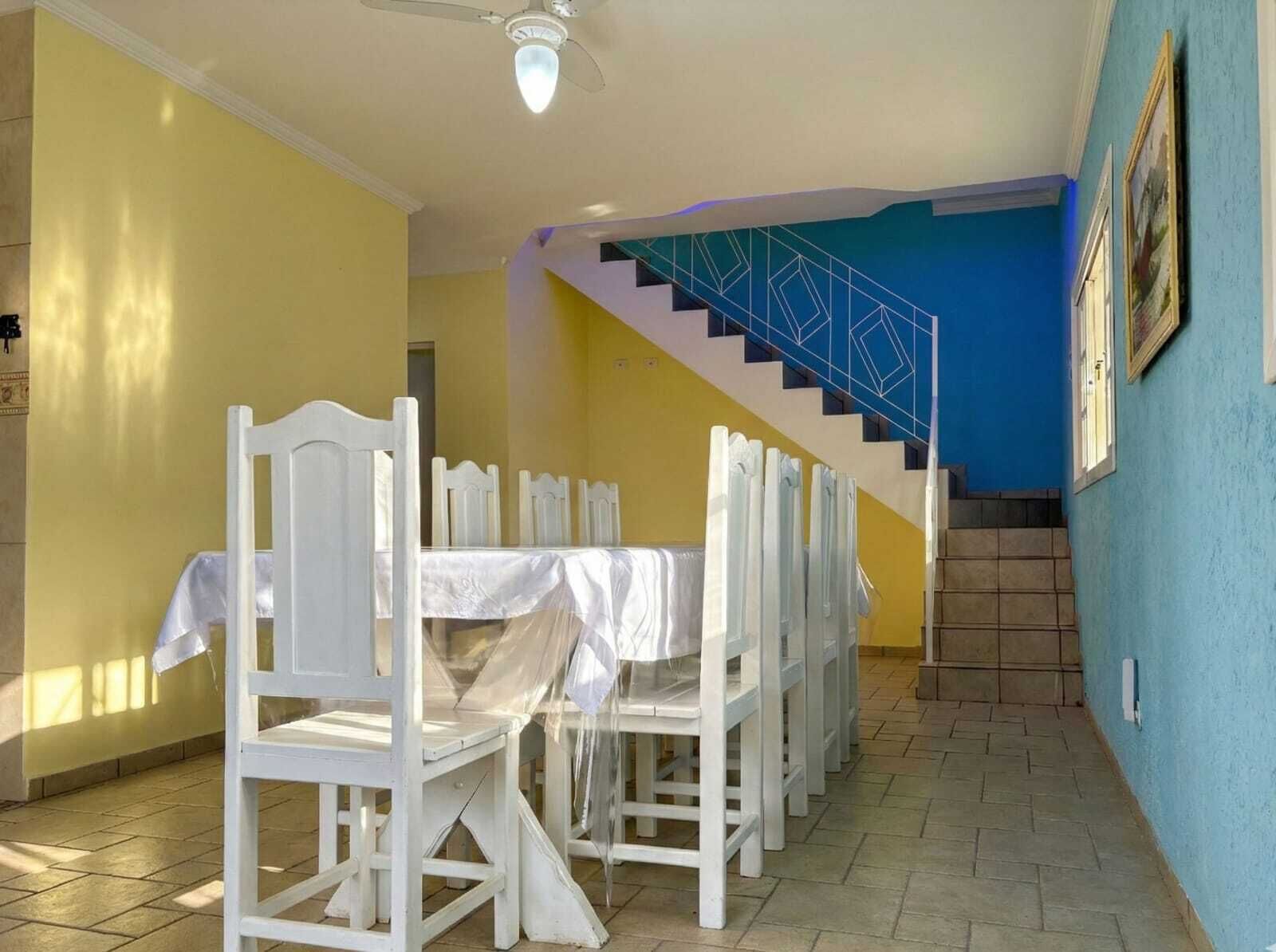 A dining area with white chairs and tables, a staircase with blue steps, and a ceiling fan.