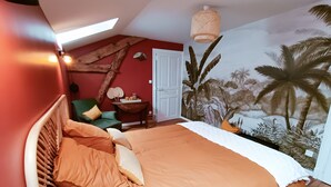 A bedroom with a bed, a chair, a small table with items, a door, and a wall mural.