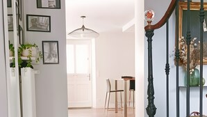 A hallway with a staircase, a dining area, and a door leading to another room.