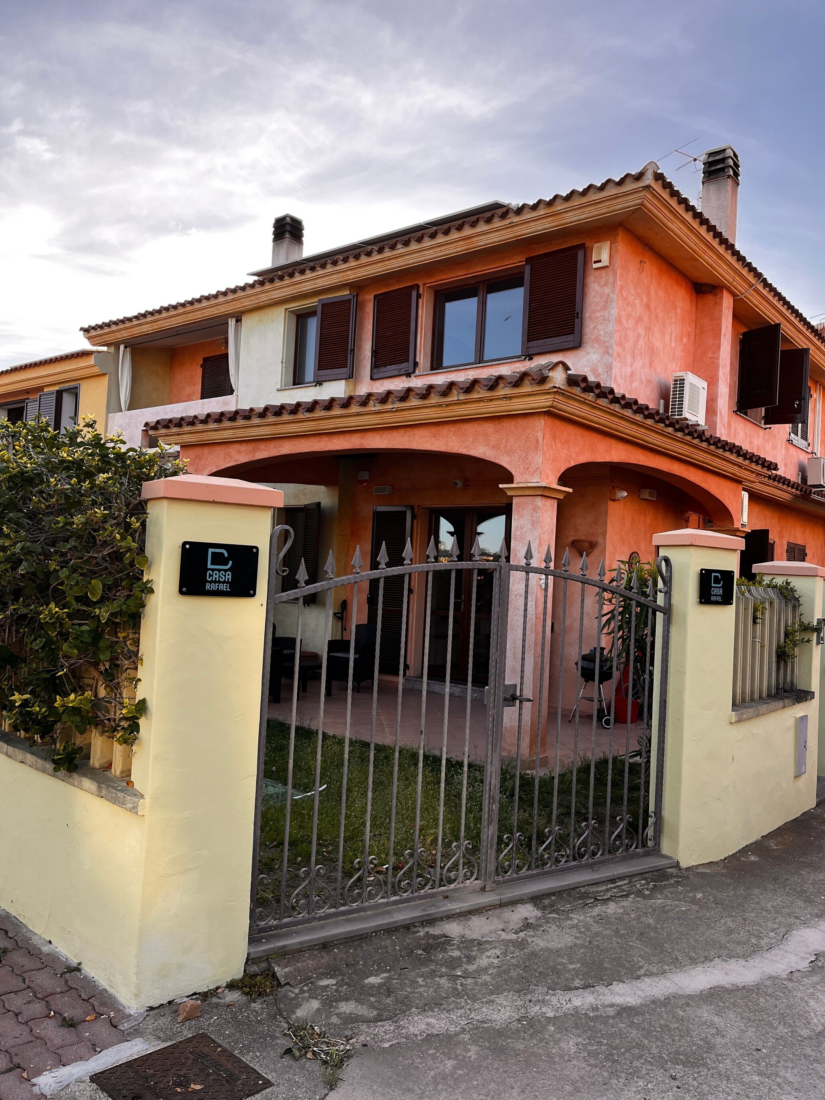 Une maison à deux étages avec une entrée fermée par un portail, un balcon et une cheminée.