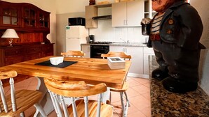 A dining area with a wooden table and chairs, a kitchen in the background, and a statue on the counter. - Holiday Home 'Rafael Villasimius House' with Private Garden, Wi-Fi and Air Conditioning (Villasimius)