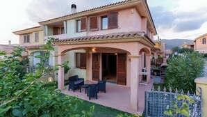 A two-story house with a patio area, outdoor furniture, and a gate. - Holiday Home 'Rafael Villasimius House' with Private Garden, Wi-Fi and Air Conditioning (Villasimius)