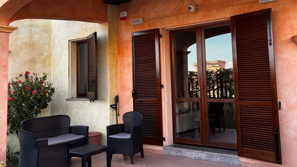A covered outdoor seating area with wicker furniture, a tiled floor, and a view of the surrounding landscape. - Holiday Home 'Rafael Villasimius House' with Private Garden, Wi-Fi and Air Conditioning (Villasimius)