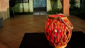 A lantern on a table in an outdoor area with a building in the background. - Holiday Home 'Rafael Villasimius House' with Private Garden, Wi-Fi and Air Conditioning (Villasimius)