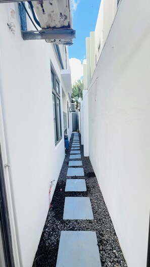 Un carrer estret amb un camí de grava negra i pedres per pisar.