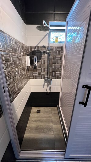 A shower with a patterned tile wall, a handheld showerhead, and a visible drain. - Modern 2 Bedroom with AC Pereybere Near Beach (Grand Baie)