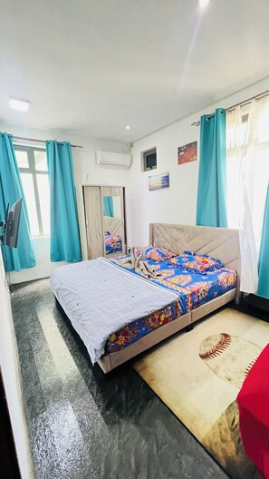 Une chambre à coucher avec un lit, des rideaux, un miroir et un climatiseur fixé au mur.