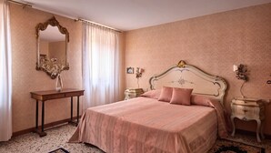 Une chambre à coucher avec un grand lit, une table de chevet, une commode, un miroir et une fenêtre avec des rideaux.