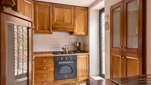 Une cuisine avec des meubles de rangement en bois, une cuisinière et une machine à café.