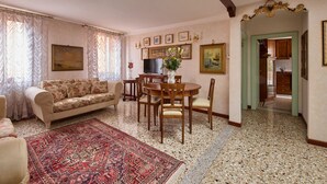 Un salon avec un canapé, une table à manger, des chaises, un téléviseur et un tapis.