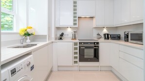 Cozinha moderna com armários brancos, forno embutido, micro-ondas e máquina de lavar.