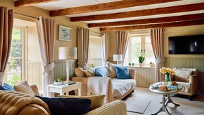 A cozy living room with a sofa, armchairs, a coffee table, and a TV mounted on the wall. - Rosedale Cottage (Brixham)