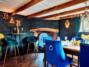 Ein rustikales Interieur mit freiliegenden Holzbalken, einer Steinwand und einer Bar mit beleuchteten Buchstaben.