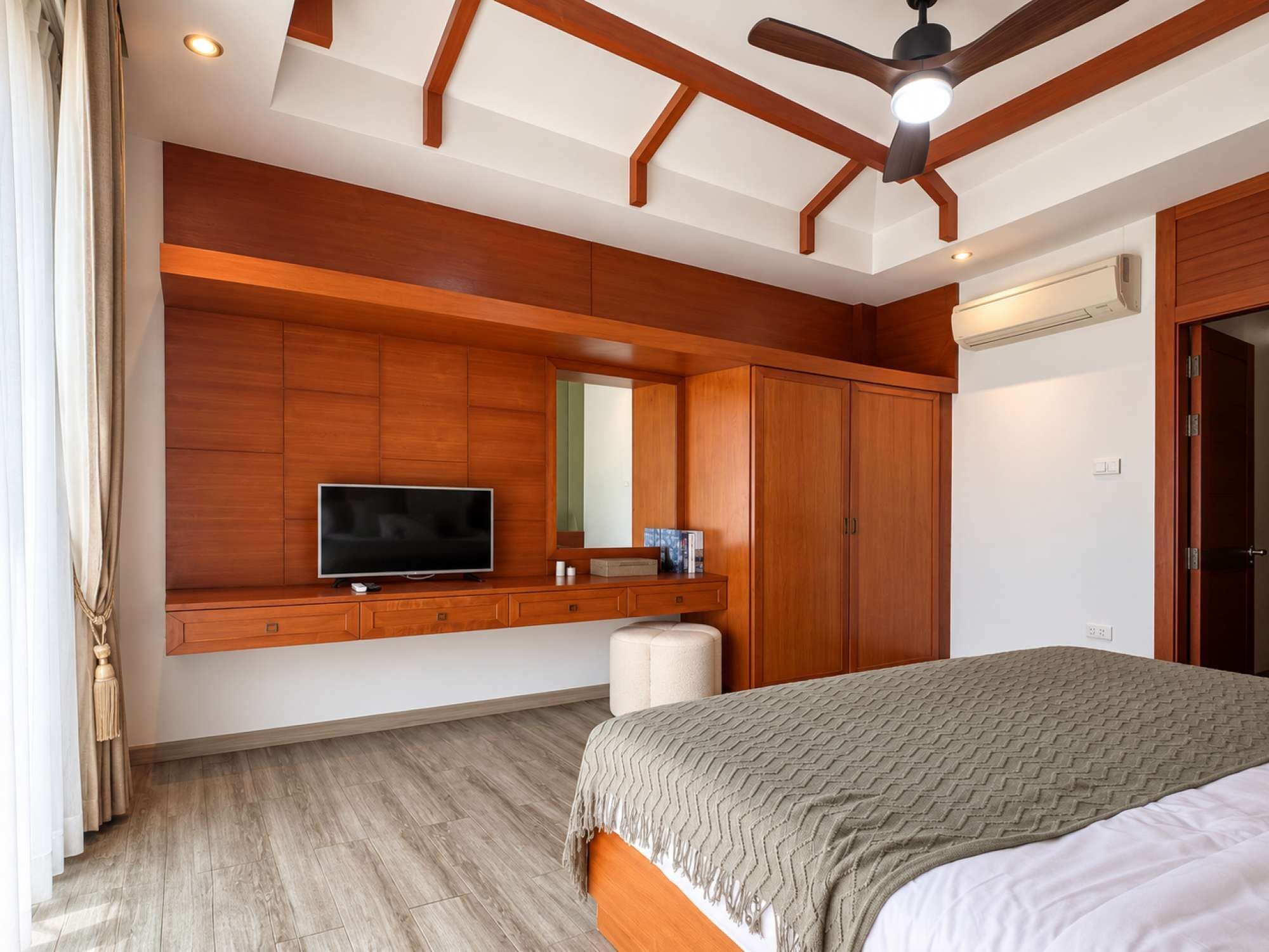 Une chambre à coucher comprenant un lit, un téléviseur, une armoire et un ventilateur de plafond.